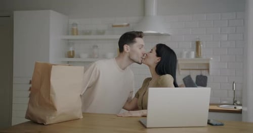 Couple Unpacking Groceries in Bright Kitchen Together