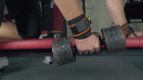 Bodybuilder Lifts the Dumbbells at the Gym