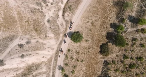 Group of people on horseback riding down a dirt road in a desert landscape, Cappadocia, Turkey
