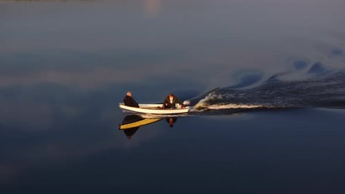 Zwei Fischer genießen einen ruhigen Abend auf ihrem kleinen Motorboot über das glatte Wasser von