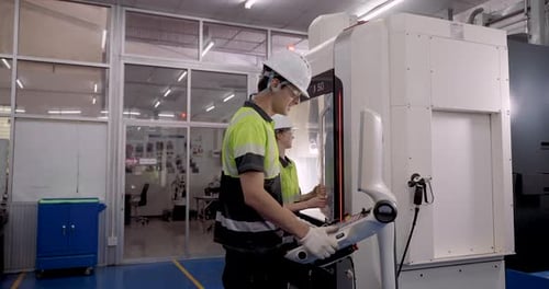male and female technicians operating cnc machine panel during slowmotion industrial training