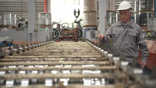 Senior experienced technician checking large machine on a production line at an industrial factory