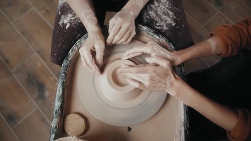 Potters shaping clay on a pottery wheel