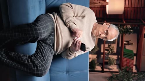 Senior Adult Relaxing on Couch Using Smartphone