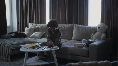 Student Studies Homework At Home on Couch