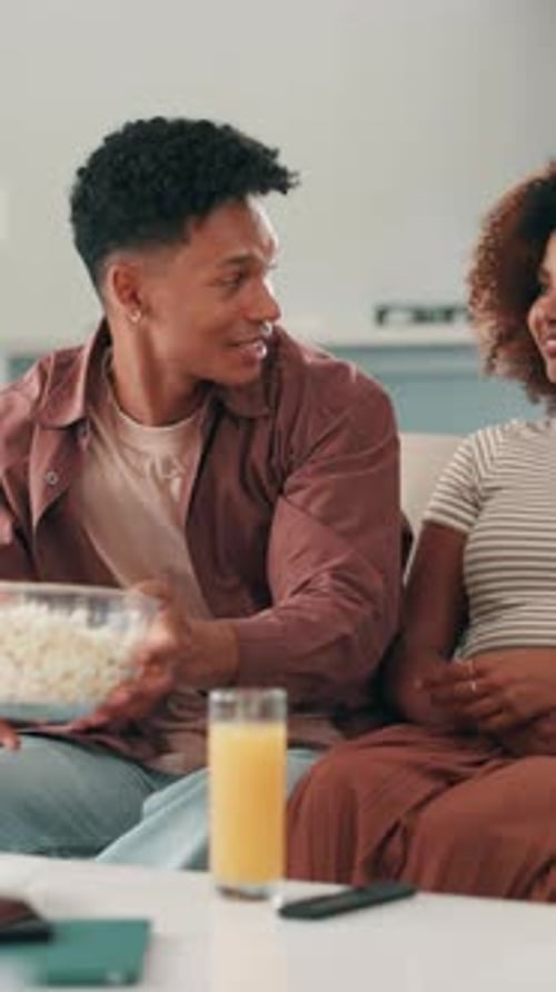 Happy Couple Relaxing and Eating Popcorn at Home