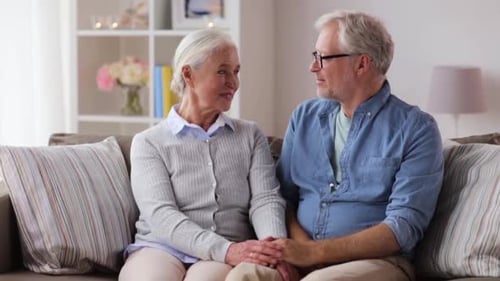 Senior Couple Holding Hands and Embracing on Sofa