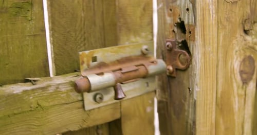 Man Closes Gate and Latches Old Sliding Lock
