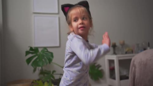 Happy Child Dancing in Pajamas with Cat Ears