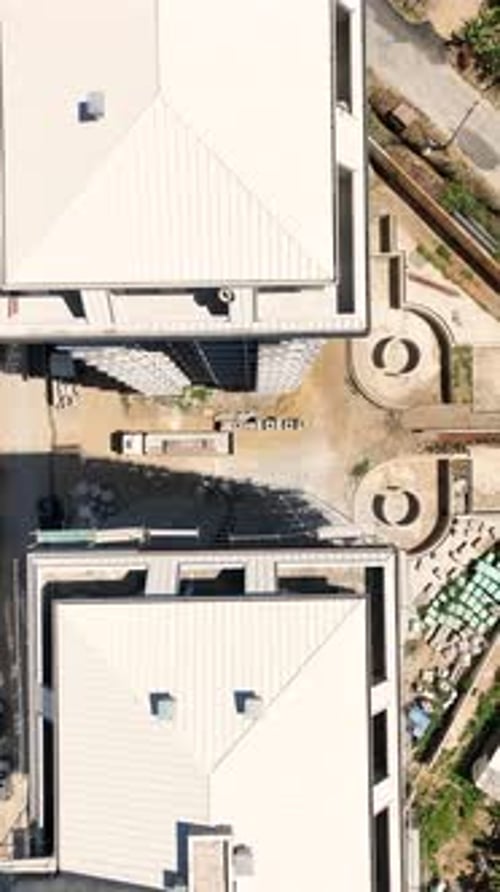 Vertical Video Aerial Shot of a Construction Project with Cranes Trucks and Workers Building