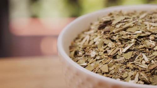 Thé maté, feuille d'Amérique latine (Ilex paraguariensis) dans un bol en céramique marron, épices séchées