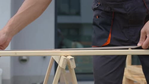 Carpenter Measuring Wooden Board with Tape Measure