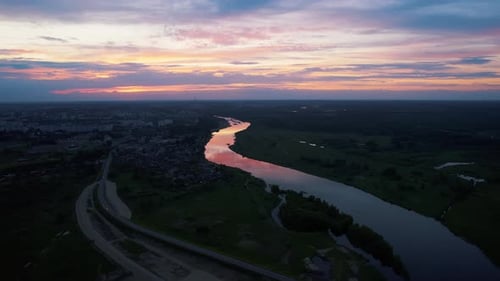 Aerial View of the City on the Banks of the River at Sunset and the Movement of Cars on the Bridge