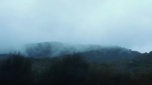 Rolling Clouds Over Forested Mountains During Foggy Morning. - POV - View From Moving Car