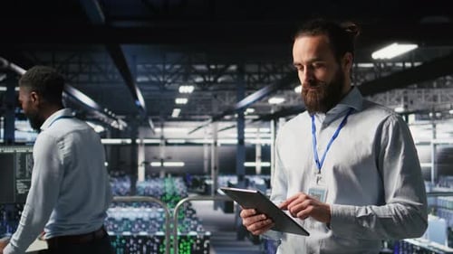 Cheerful Data Center Admin Doing Maintenance Tasks on Tablet