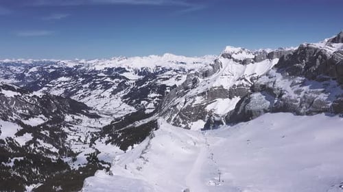 Stunning drone footage high over a ski run in the Swiss Alps. The drone passes over the ski run and