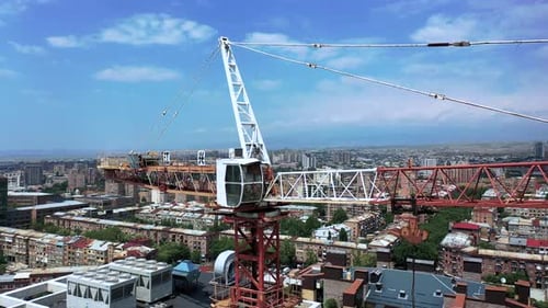 Construction crane near building. Drone fly around crane in the city.