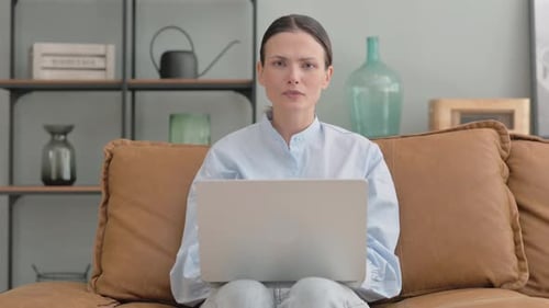 Woman Using Laptop at Home Frowning