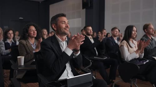 People at business conference give applause to speaker in corporate auditorium