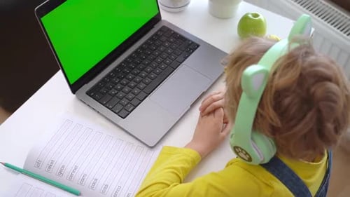Child with Laptop and Green Screen at Desk