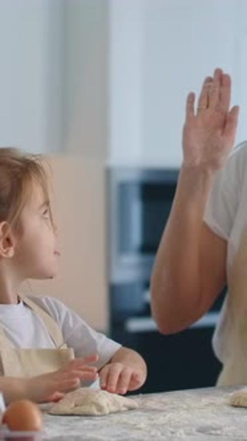 Mother and Daughter Wearing Aprons Enjoy a Fun Baking Activity Together in a Bright Home Kitchen