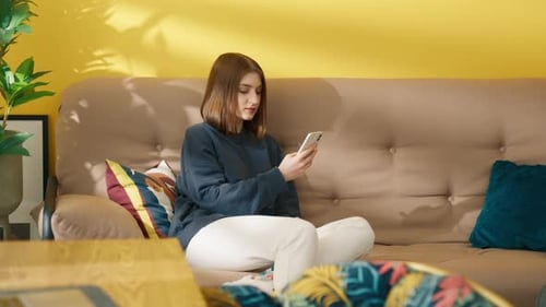 Woman Using Mobile Phone on Couch Indoors