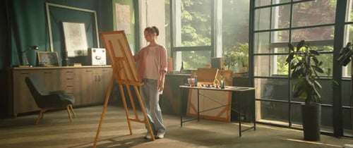 Young Woman Artist Painting Picture on Canvas in Big Art Studio Workspace Light Room Creative