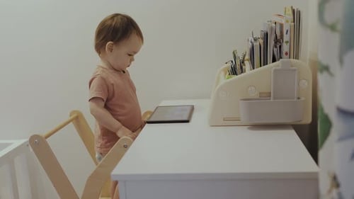 Baby using a tablet in bright modern playroom