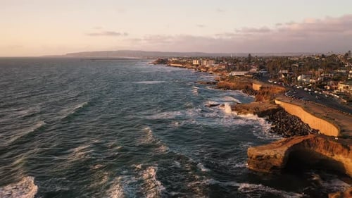 Aerial dolly at sunset with ocean waves along Sunset Cliffs in San Diego