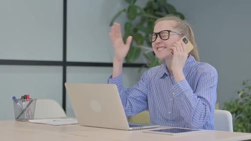 Young Adult Talking on Phone at Desk