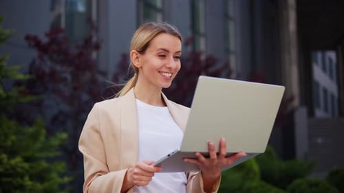 Smiling Woman Uses Laptop for Video Call Outdoors