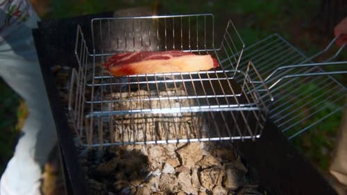 Close-up of man grilling pieces of red meat