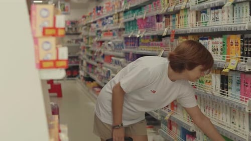 Young Woman Choosing Shampoo in the Supermarket Close Up