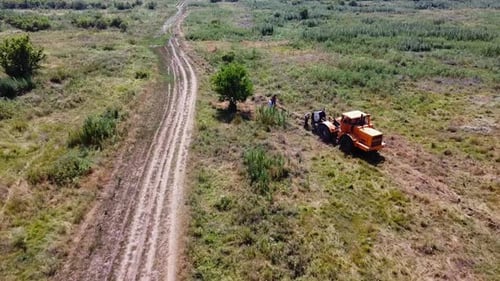 Aerial View of Tractor with a Cable Drum Laying Fiber Optic Hawser at Countryside Workers Guiding