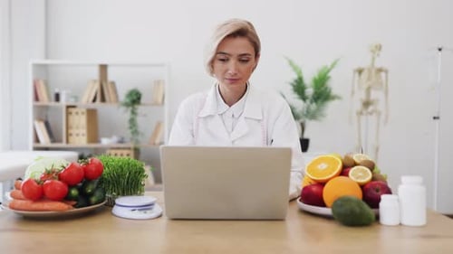 Smiling Dietician at Desk with Fruits and Vegetables