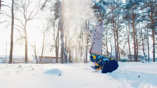 Winterlicher Familienspaß. Junge Mutter spielt mit ihrem Kleinkind im Wintergarten und wirft
den Schnee