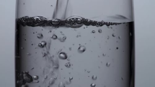 Close Up Of Drinking Water Being Poured Into A Glass On The Light White Screen Background