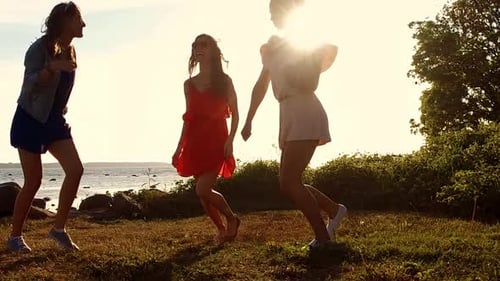 Three Young Women Dancing at Sunset near the Beach