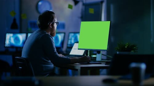Creative Bearded Man arbeitet an einem PC mit isoliertem Mock-up-Greenscreen. Er arbeitet alleine