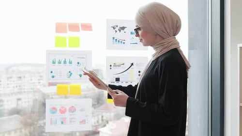 Woman Reviews Data Charts in Bright Modern Office