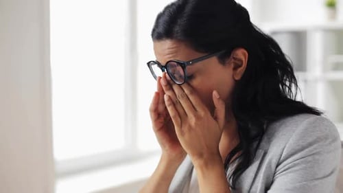 Tired Woman Rubbing Eyes in Office