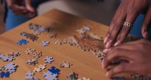 Primer plano de las manos de personas de apariencia africana haciendo rompecabezas