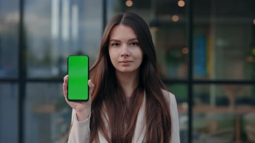 Stylish Young Woman Displays Green Screen Smartphone Mockup Outdoors Near Office Center Portrait of