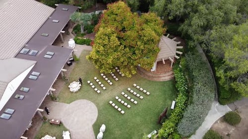 Aerial view of an outdoor wedding celebration setup with white chairs on a green lawn. Rancho Santa