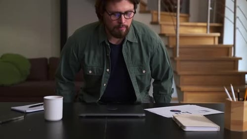 Young Man Sits Down at Desk and Opens Laptop to Working in Home Office Spbas