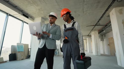 Architect and Construction Worker Discussing Building Plans on Laptop