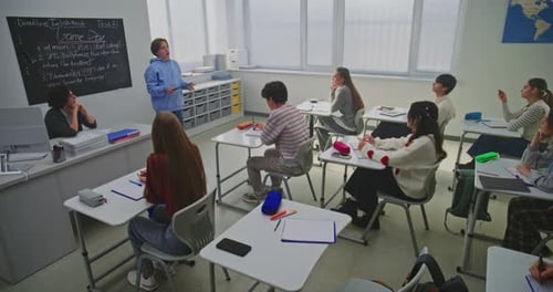 Teenage Boy in Blue Hoodie Confidently Presents Game Development Project Classmates and Teacher