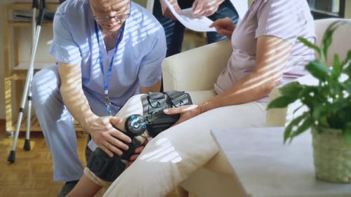Healthcare Worker Fitting Knee Brace on Senior Woman