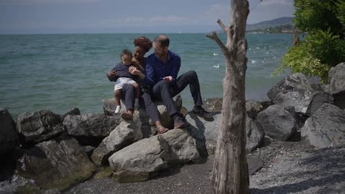 Family Sitting on Rocks by Ocean