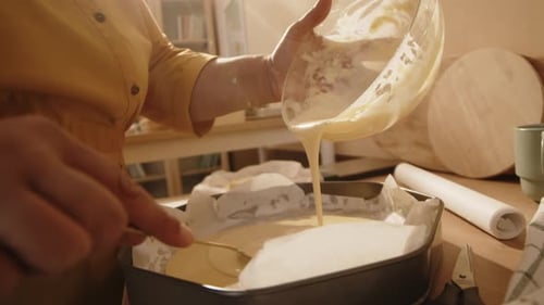Woman Pouring Batter into Cake Form while Baking at Home
